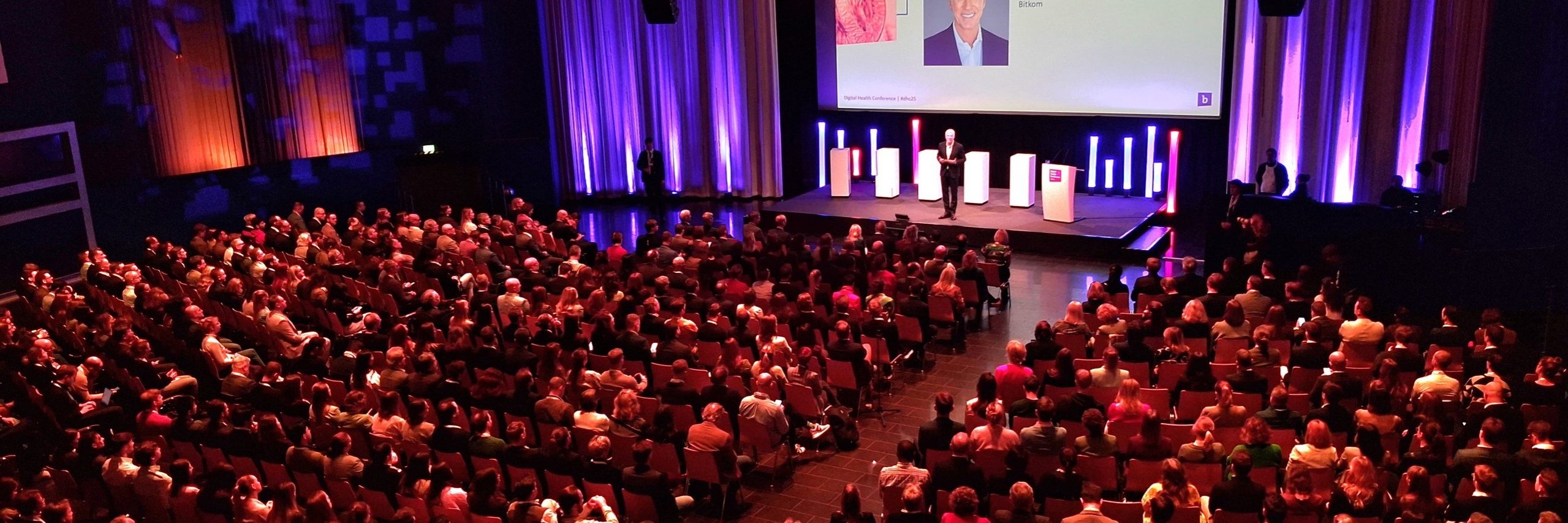 Der Hauptsaal mit Reihenbestuhlung und Ambientebeleuchtung.