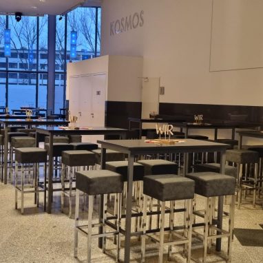 Blick in das Foyer mit Stehtischen und Sehhockern.